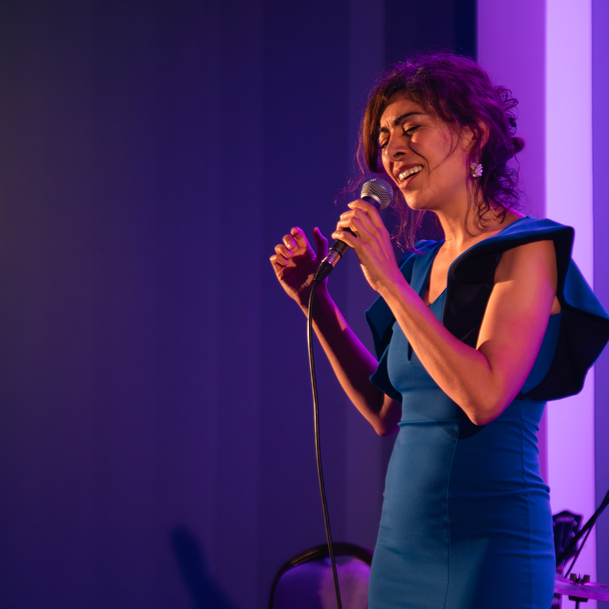 Una cantante en un escenario, con iluminación violeta