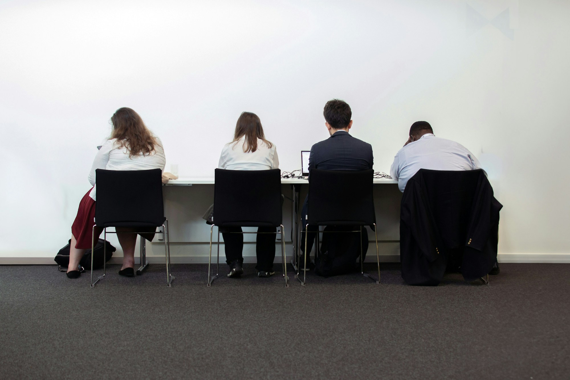 Varias personas evaluando cada una en su propio puesto, de espaldas entre sí, sin verse